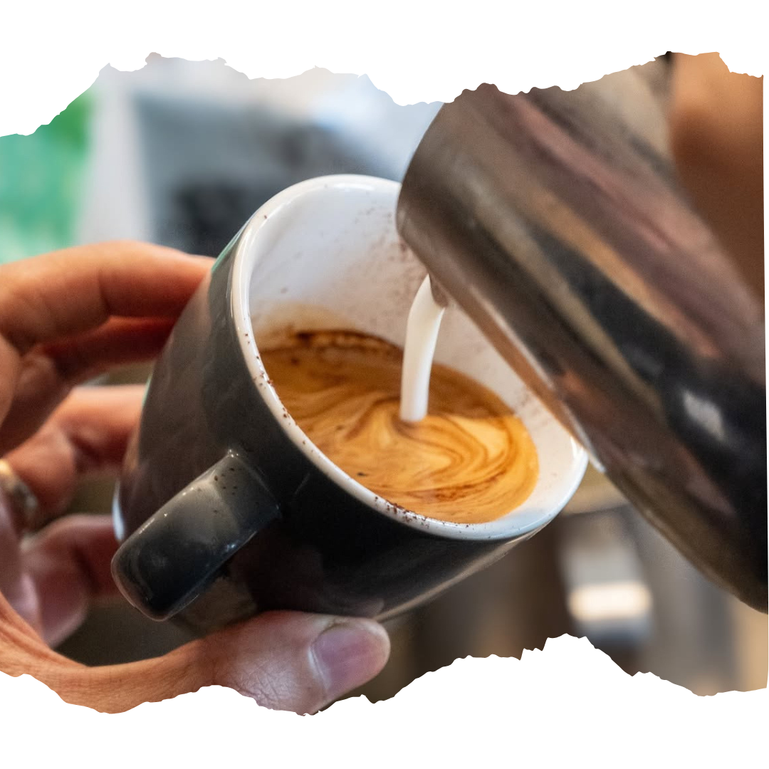 frothed milk being poured into a coffee mug