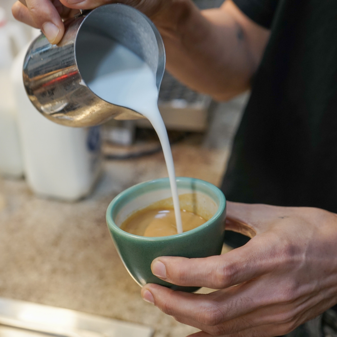 Milk being poured into a latte - Coffee by Black Market Coffee